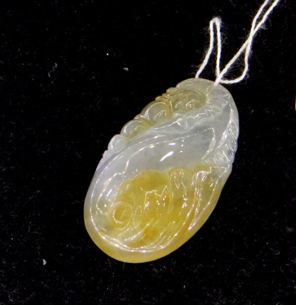 A stunning close-up of the Natural Jadeite Dragon Spitting Pearl Pendant, showcasing its intricate dragon carving and lustrous 18K gold clasp. The jadeite's warm tones and translucent details highlight its premium craftsmanship.