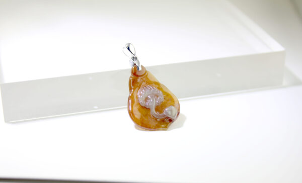 A stunning close-up of the Natural Ice Yellow Jadeite Magnolia Pendant, showcasing its delicate honey-like hue and intricate hand-carved magnolia petals, set with a sleek 18K white gold clasp.
