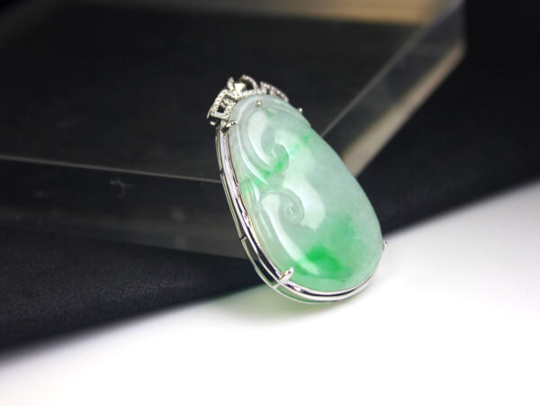 A stunning Natural Emerald Ruyi Pendant featuring ice-type floating green emerald, elegantly inlaid with 18K white gold and sparkling diamonds, showcasing traditional oriental design with modern craftsmanship.