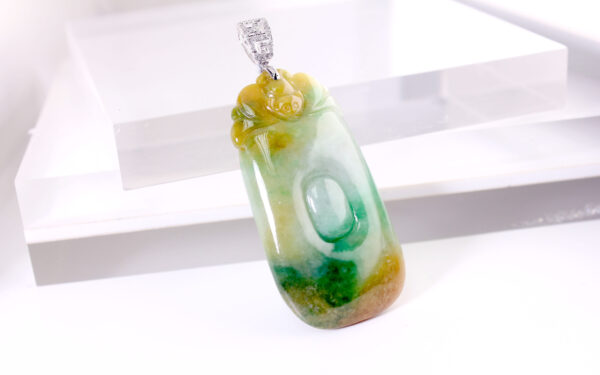 A stunning close-up of the Natural Jadeite "Fu, Lu, Shou" Pendant, showcasing its harmonious green, yellow, and white hues. The 18K white gold and diamond clasp adds a luxurious touch, making it a perfect fusion of tradition and modernity.