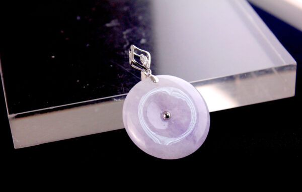 A stunning close-up of the Natural Ice-type Violet Jade Peace Buckle Pendant, showcasing its delicate light purple hue, intricate 18K white gold inlay, and sparkling diamonds, set against a luxurious backdrop.