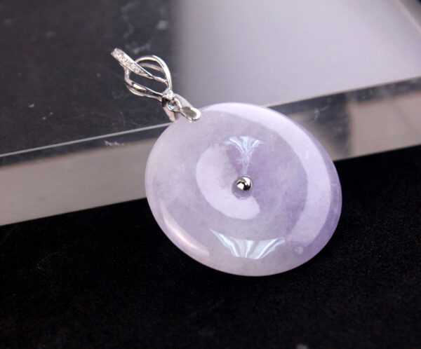 A stunning close-up of the Natural Ice-type Violet Jade Peace Button Pendant, showcasing its clear, ice-like texture and elegant violet hue. The 18K white gold setting and sparkling diamond accents highlight the pendant's intricate craftsmanship and timeless beauty.