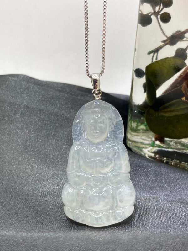 A stunning close-up of the Natural Ice-white Jadeite Avalokitesvara Pendant, showcasing its delicate carving, translucent ice-white jadeite, and elegant 18K white gold clasp. The pendant rests gracefully on a soft velvet background, highlighting its intricate details and serene beauty.