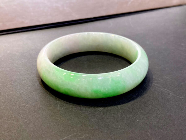 A stunning close-up of the Natural Jadeite Ice Bean Bracelet, showcasing its translucent ice bean texture and naturally distributed emerald green veins, resting elegantly on a silk cloth.