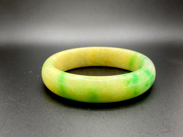 A beautifully polished Natural Emerald Bracelet showcasing a harmonious mix of Spicy Green and Chicken Fat Yellow colors. The smooth, lustrous surface highlights the glassy luster and natural stone veins, making it a unique and eye-catching piece.
