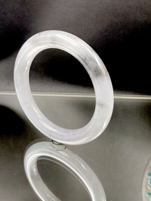 A stunning Natural Ice-type Black Chicken Jadeite Bracelet showcasing its translucent ice-clear base with striking grayish-black ink-like patterns. The smooth round-bar design highlights traditional craftsmanship and modern elegance.