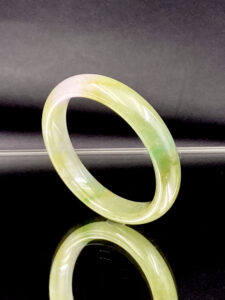 A stunning Natural Ice-Type Yellow-and-Green Jadeite Bracelet (51mm) showcasing a translucent ice-crystal texture with interwoven yellow and green hues. The polished round-strip design ensures comfort and elegance, making it a perfect accessory for any occasion.