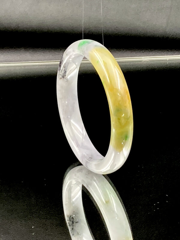 A stunning Natural Ice-type Yellow-and-Green Black-spotted Jade Bracelet, showcasing a smooth, translucent jade surface with vibrant yellow and green hues intertwined with artistic black-spotted patterns. The bracelet’s polished round-bar design ensures a comfortable fit, highlighting its natural beauty and craftsmanship.