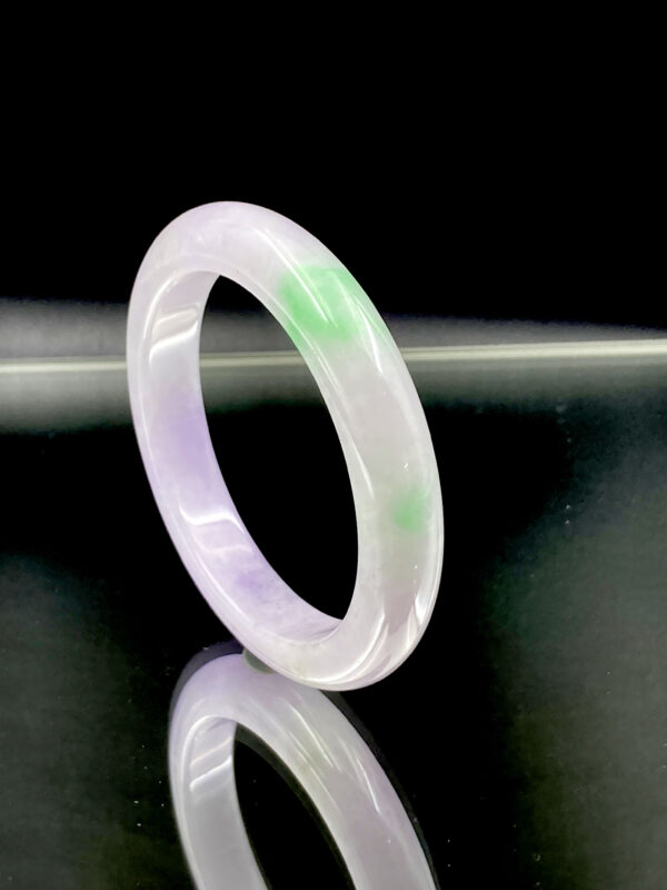 A stunning close-up of the Natural Ice-Type Violet and Vivid Green Jadeite Bracelet, showcasing its clear, icy texture and the seamless blend of violet and vivid green colors. The smooth, polished round-strip design enhances its elegance, making it a must-have for jadeite lovers.