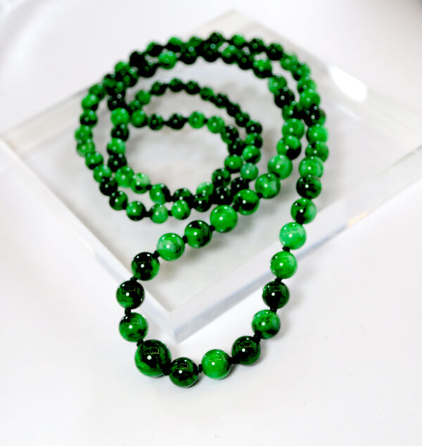 A stunning close-up of Natural Flower-veined Jade Pagoda Beads, highlighting the intricate color veins and smooth polish of each round bead, elegantly draped or layered for versatile wear.