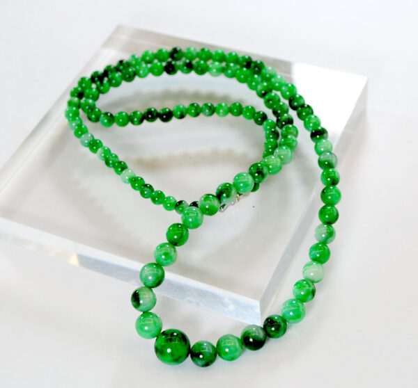 A stunning close-up of the Natural Jadeite Flower-Green Pagoda Beads Necklace, highlighting the rich emerald-green hues and intricate natural patterns of each jadeite bead. The necklace is elegantly draped, showcasing its smooth polish and lustrous glass-like finish.