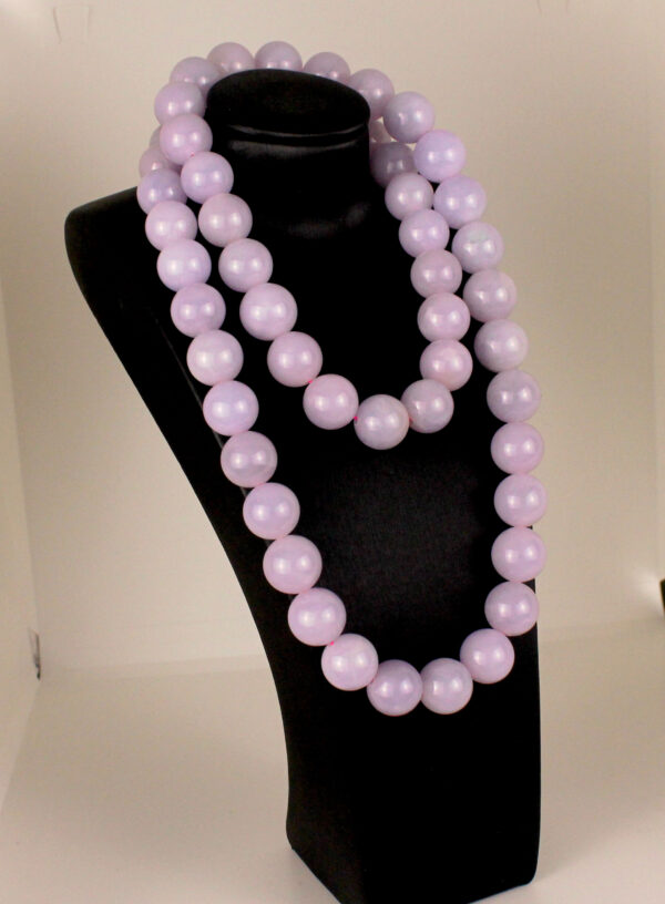 A stunning close-up of natural violet jadeite beads with a smooth, polished surface, showcasing their soft purple-to-pink gradient. The 18K white gold clasp adds a refined touch, complementing the beads' elegance.