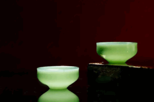 Evening scene: warm lantern glow over tea set and scattered jade carvings on courtyard stone floor.