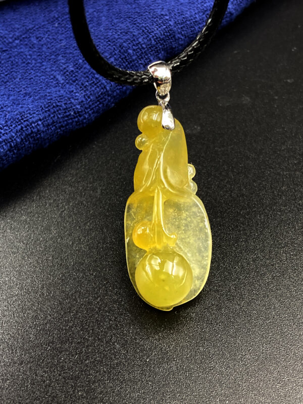 A stunning icy yellow jadeite pendant carved into a delicate magnolia flower, showcasing intricate details and a smooth, lustrous finish. Paired with an 18K gold diamond clasp for added elegance.