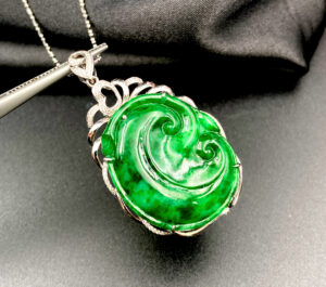 A stunning Flower Green Jadeite Pendant featuring swirling natural patterns, set in 18K white gold with sparkling diamond accents. The heart-shaped clasp adds a delicate touch, making it a versatile accessory for any outfit.