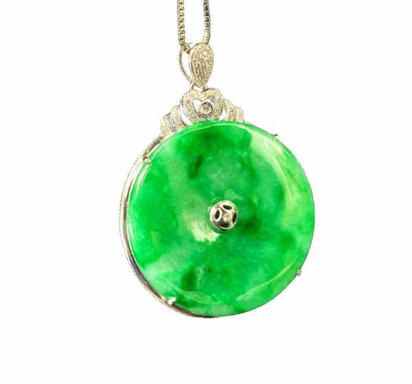 A stunning Natural Icy Flower Green Jadeite Pendant set in 18K white gold with sparkling diamonds. The jadeite displays a delicate mix of vibrant green and subtle cyan hues, polished to a smooth, round-edged antique-inspired design for timeless elegance.
