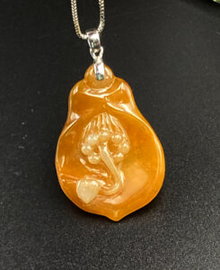 A stunning close-up of the Natural Ice Yellow Jadeite Magnolia Pendant, showcasing its warm golden hue, delicate floral carving, and sleek 18K white gold clasp on a neutral background.