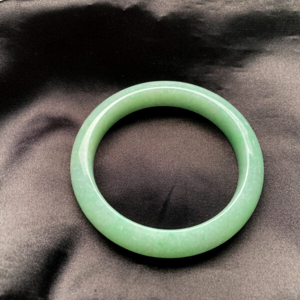A beautifully polished Natural Jadeite Douqing Bracelet with a smooth round-bar design, showcasing the gentle Douqing color and delicate texture of authentic jadeite.