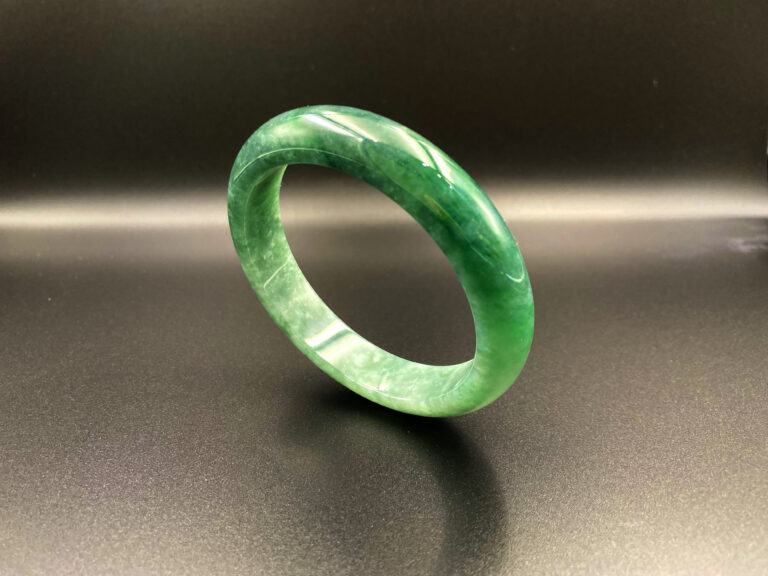 A stunning icy green jadeite bangle with a smooth, glossy finish, showcasing vibrant, evenly distributed color and fine craftsmanship.
