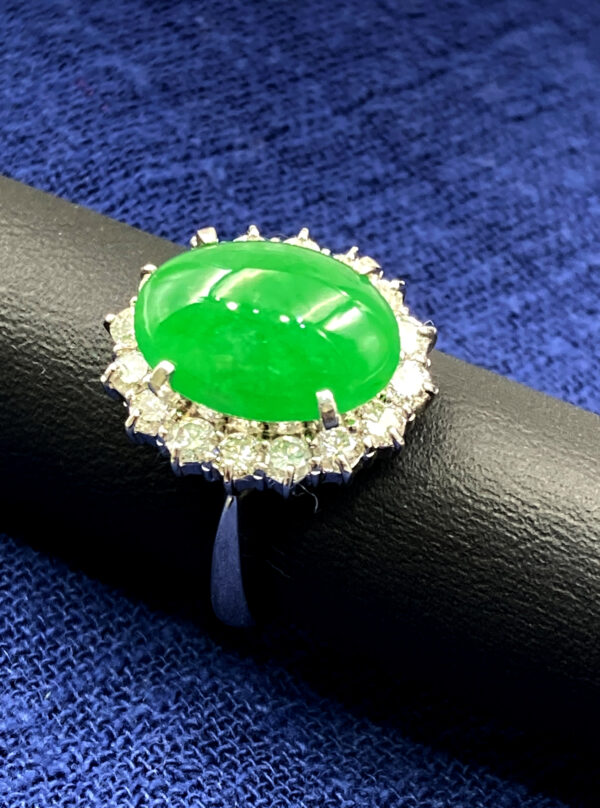 A stunning close-up of a natural emerald cabochon ring, showcasing its rich green hue and sparkling diamond accents set in lustrous platinum. The elegant design highlights the perfect fusion of tradition and modernity.