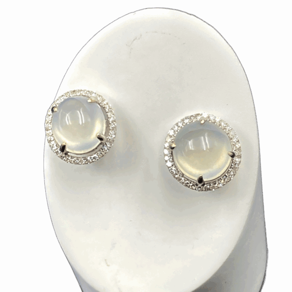 A stunning pair of high-ice jadeite earrings featuring a translucent 9.5x9.5x7 mm jadeite egg face, meticulously set in 18K white gold and encircled by brilliant diamonds. The jadeite’s smooth polish and natural glow are enhanced by the diamond halo, creating a luxurious and refined aesthetic.