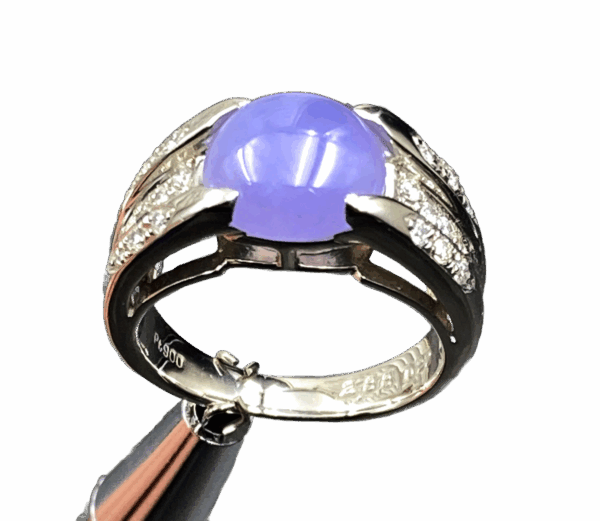 A stunning close-up of the Natural Ice-type Violet Jade Cabochon Ring, showcasing its translucent violet hue, 22K white gold band, and sparkling diamond accents on a velvet background.