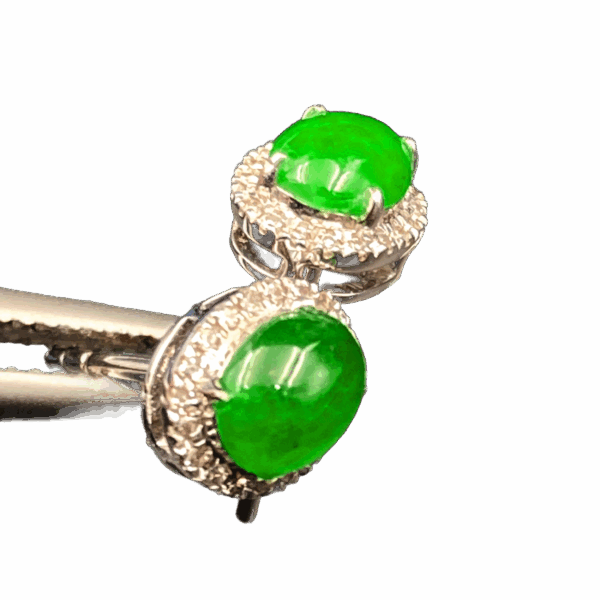 A pair of elegant oval-shaped icy jadeite earrings with a vibrant green hue, set in 18K white gold and surrounded by brilliant diamonds, showcasing a luxurious and harmonious design.