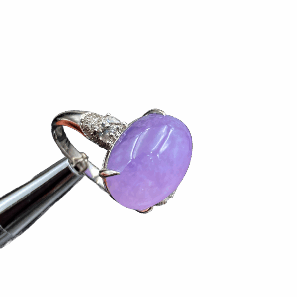 A stunning oval cabochon violet jadeite ring, showcasing vivid color and excellent transparency, set in 18K white gold with sparkling sapphires and diamonds.