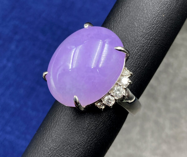 A stunning close-up of the Natural Ice-type Violet Jadeite Cabochon Ring, featuring a lustrous violet jadeite centerpiece set in gleaming platinum with delicate diamond accents. The cabochon cut highlights the jade's translucent glow, while the platinum band adds a touch of modern sophistication.