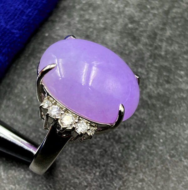 A stunning oval-shaped ice-type violet jadeite cabochon ring, set in lustrous platinum and accented with sparkling diamonds, showcasing timeless elegance.