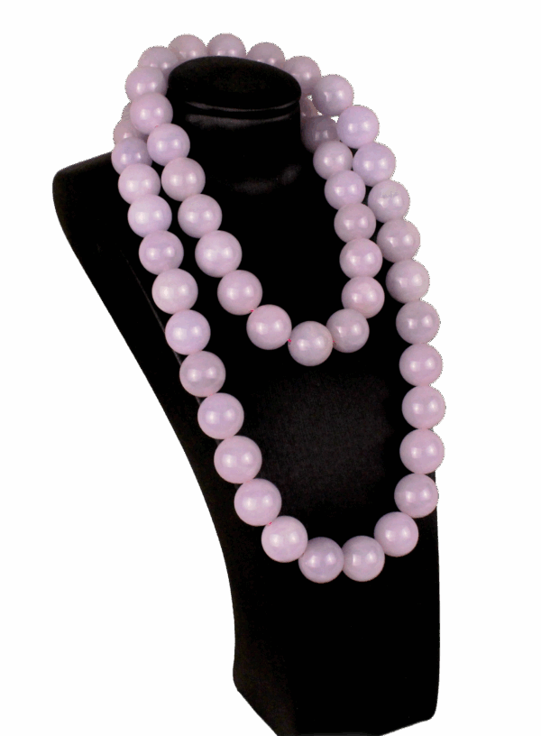 A stunning close-up of natural violet jadeite beads with a smooth, polished surface, showcasing their soft purple-to-pink gradient. The 18K white gold clasp adds a refined touch, complementing the beads' elegance.