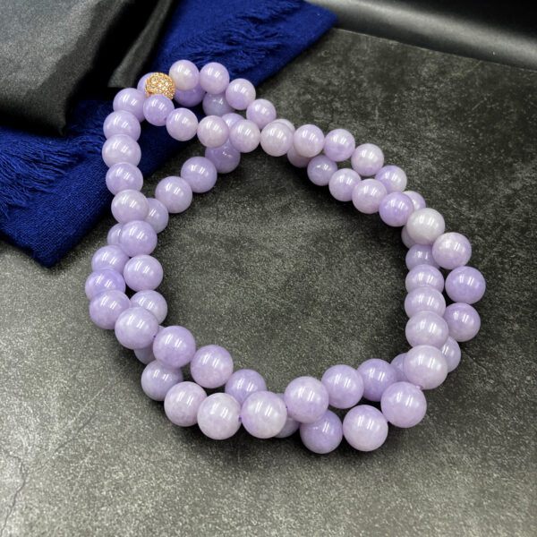 A stunning close-up of the Ice-Type Lavender Jadeite Beaded Necklace, showcasing its translucent, glossy beads in a delicate lavender hue. The 18K gold clasp embedded with diamonds adds subtle luxury, while the smooth, mirror-like finish highlights expert craftsmanship.