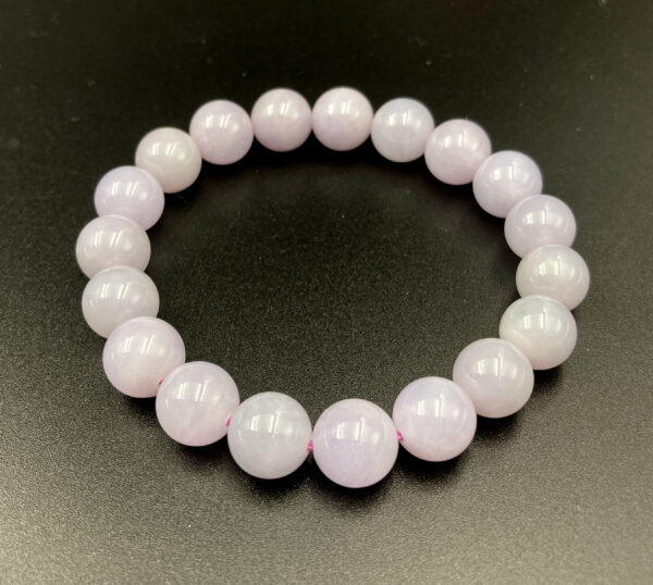 A delicate lavender-white jadeite beaded bracelet, showcasing smooth, polished beads with a soft vitreous luster, elegantly strung on an elastic cord for a natural and refined look.