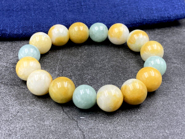 A stunning tri-color jadeite beaded bracelet showcasing harmonious yellow, white, and light green hues. Each 12mm bead is polished to a glossy finish, strung on an elastic cord for adjustable comfort. Perfect for gifting or personal collection.