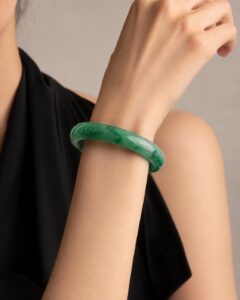 Close-up of polished green jade bangle on dark silk, soft light highlighting translucency