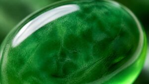 A vivid green jadeite bangle with glassy translucency on a silk surface