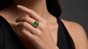 Luminous green jadeite cabochon ring on silk, soft light highlighting its translucency and smooth polish