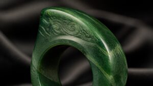A jadeite saddle ring on a silk display stand, softly lit to highlight its translucent green tones