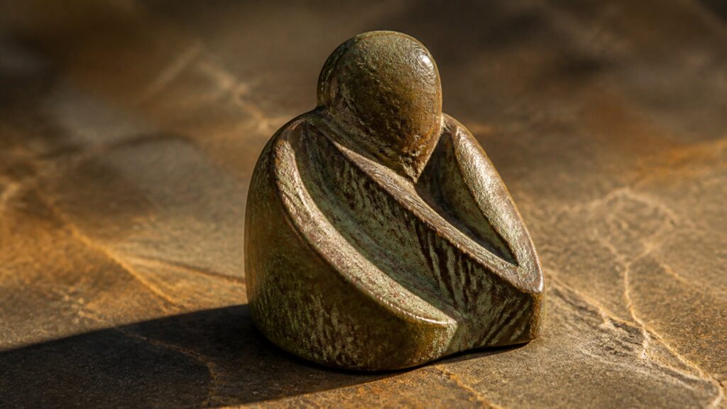 An antique Chinese bronze vessel with verdigris patina on a dark wooden stand, museum lighting