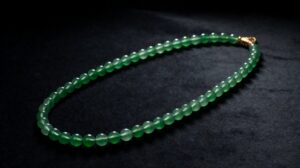 A single strand of polished green jadeite beads resting on soft cream silk in warm light
